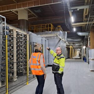 Kaksi henkilöä keskustelee tehtaassa.
