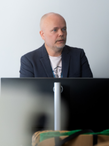 Mikko Lehtonen puhumassa tietokoneen takana sisätiloissa.